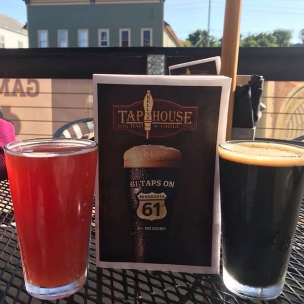 Two beers, one red and one dark, on a patio table with a Kelly's Tap House menu.